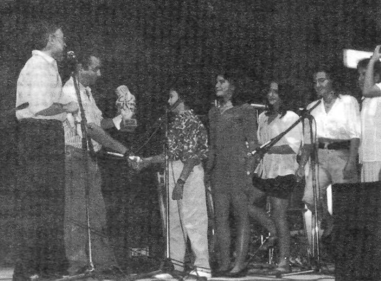 Un grup d'alumnes de l'Escola de Sant Mateu a l'escenari recollint un premi, amb micròfons davant.