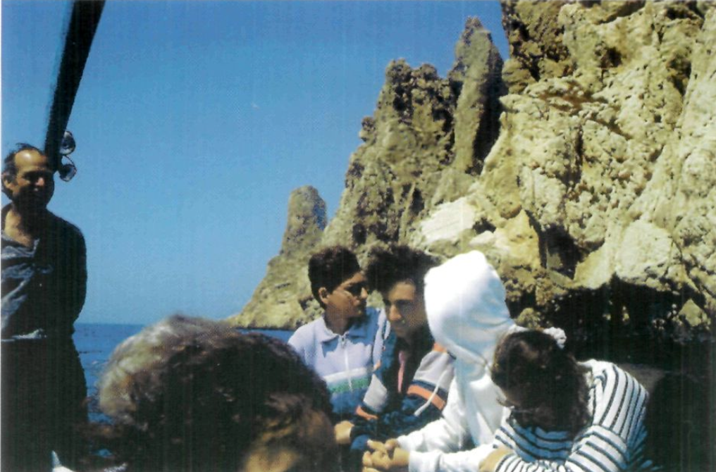 El patró Joan Sendic al timó del seu llaüt, amb el grup escolar, i el programa de l'activitat pedagògica. A la dreta el far del Vedrà, situat a la part del sudo-est de l'illot. (Fotos: Felip Cirer Costa.)