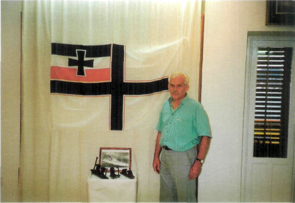 Vicent Torres davant unes bites i una guia que la tradició diu que eren del Deustchland i que caigueren a la mar, per efectes del bombardeig, amb un tros de fusta. Al fons l'antiga bandera de combat de l'esquadra alemanya.