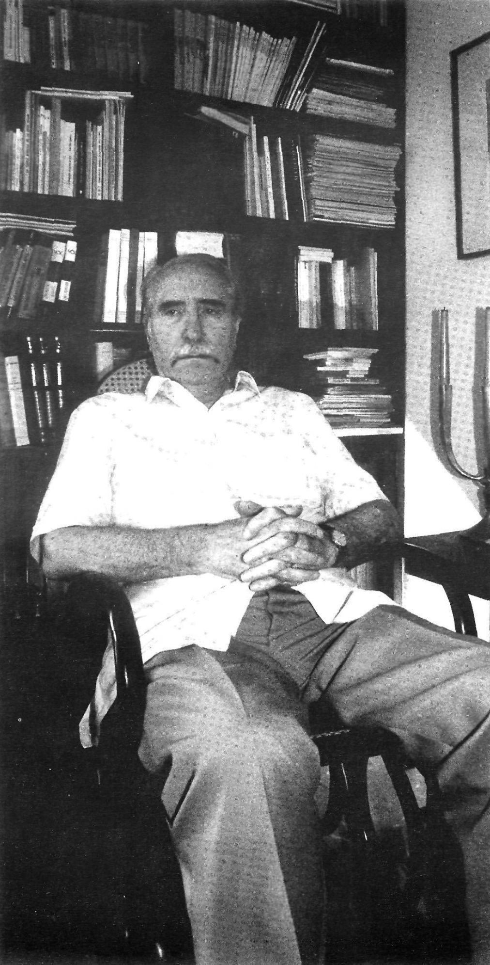 Man sitting in a chair in front of bookshelves
