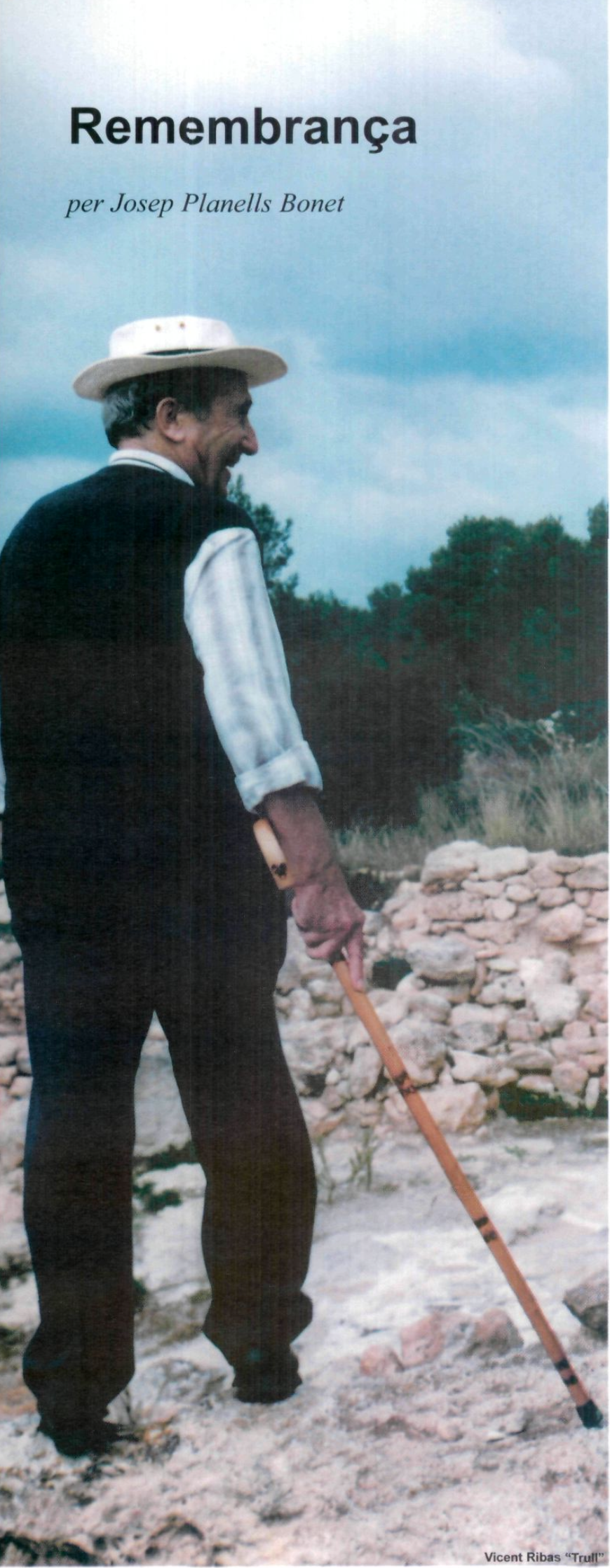 Un home gran amb barret, armilla i bastó, d'esquena parcialment girada, en un paisatge rural rocós.