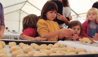 A baix, a l'esquerra, cartell anunciador de la gala de les Mencions Sant Jordi 2012 (disseny: Pep Toni). A la dreta, una moment del taller de l'elaboració de panellets en la festa de la Trencada de pinyons (fotografia: Carles Torres).
