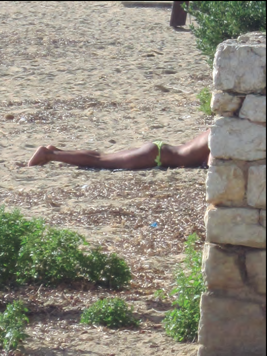 Person lying on a wall by the sea