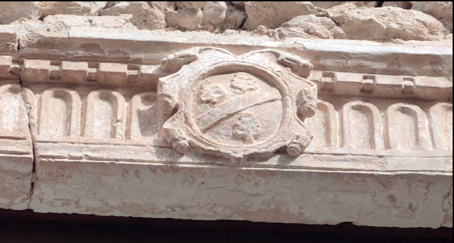 A la fotografia superior, imatge actual de l'escut que figura a la llinda del finestral del primer pis de can Miqueleta, al carrer de la Soledat 1, abans carrer del Cementeri.