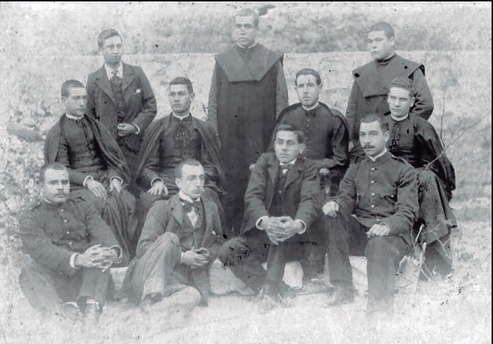 Isidor Macabich (segon per l'esquerra, assegut), vestit de paisà, amb diversos companys de seminari, alguns dels quals amb vestimenta eclesiàstica i altres amb uniforme de soldat.