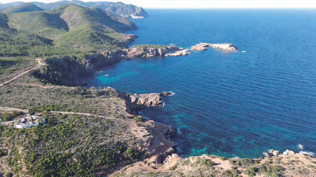 Vista aèria del tram de costa entre els pobles de Sant Joan de Labritja i Sant Miquel de Balansat, amb el caló de sa Fusta en primer terme i l'illa d'Encalders al centre de la imatge (fotografia d'Iñaki de Eróstegui Aznar).