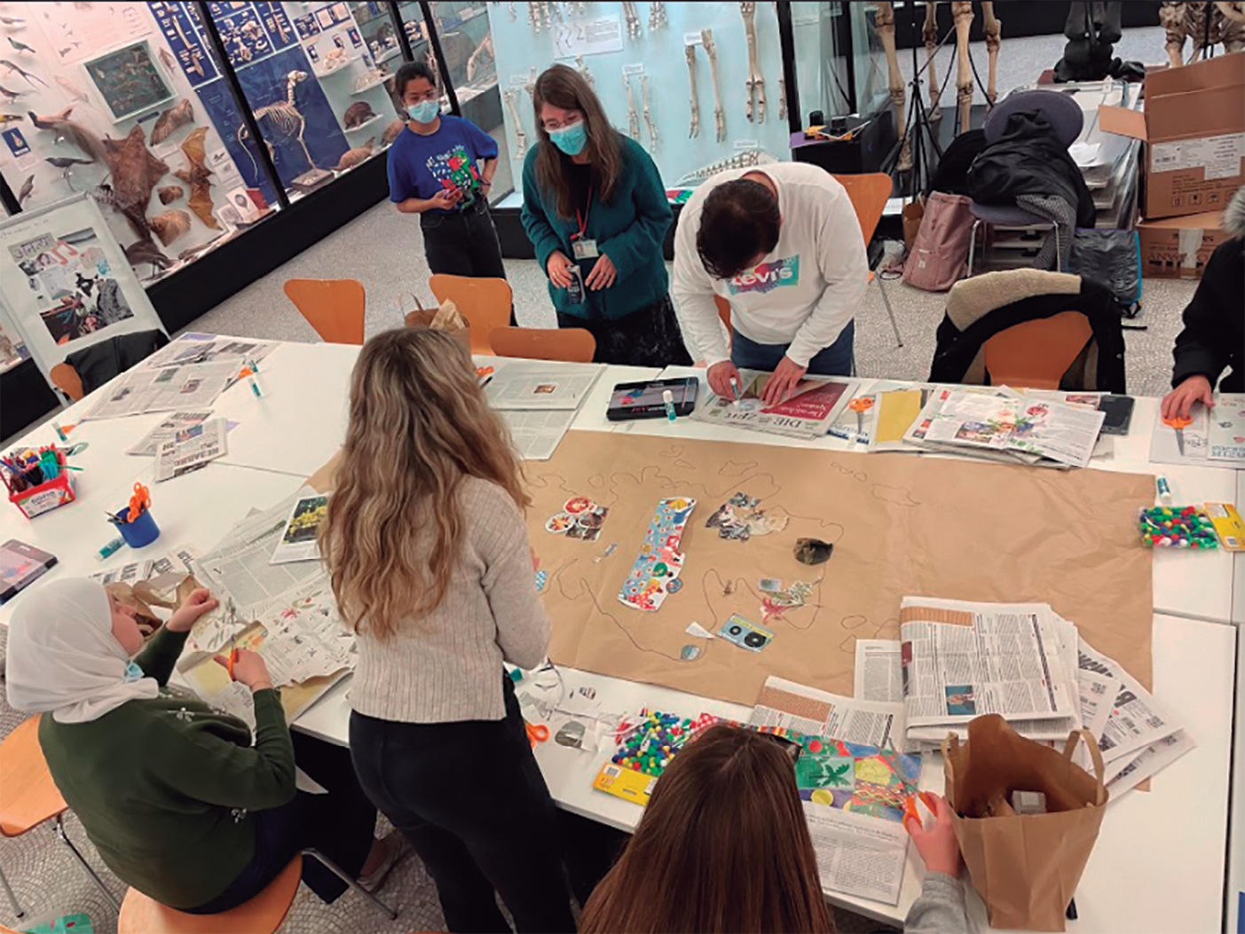 Un grup de persones al voltant d'una gran taula amb un mapa, participant en un projecte educatiu.