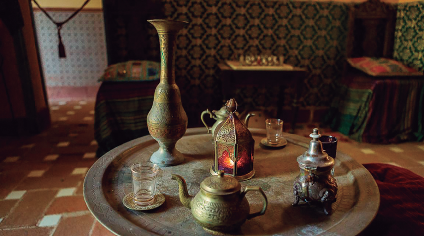 Interior d'una sala de te d'estil àrab, amb coixins a terra, una taula baixa amb teteres i gots.
