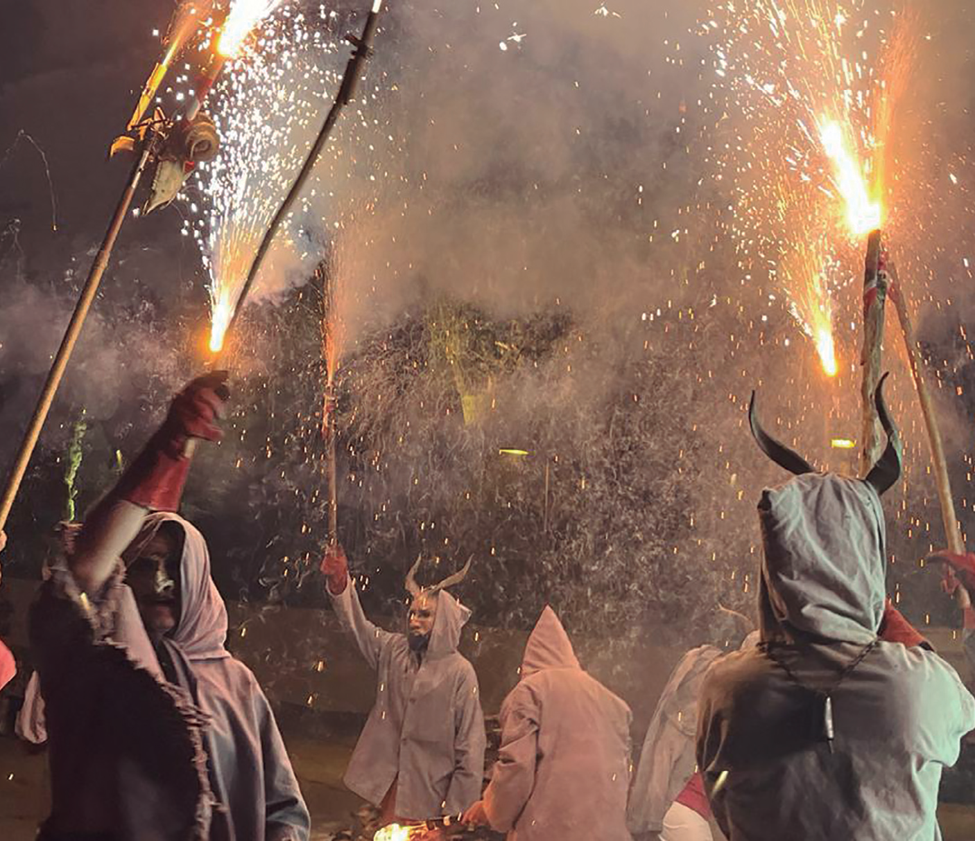 Imatge d'un correfoc durant la Nit de Sant Joan, amb persones vestides de dimonis sostenint bengales.